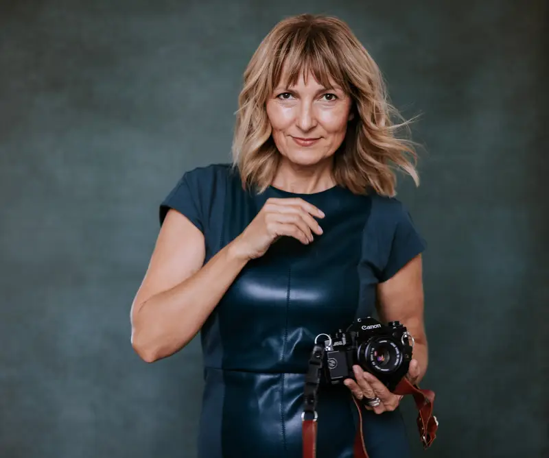 Jola Bremer holding her camera against a dark backdrop